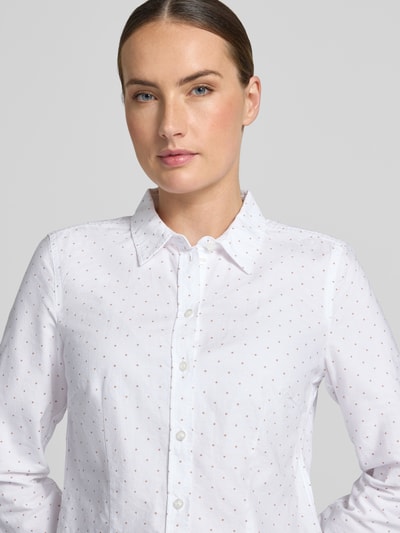 Vrouwenmodel draagt Bluse mit Hemdblusenkragen und Knopfleiste van Christian Berg Woman, puur katoen, licht getailleerd model, overhemdkraag, knoopsluiting, afgeronde zoom, ruglengte maat 36: 62 cm, mouwlengte maat 36: 59 cm, witte stof met kleine stippen, Nahaufnahme bovenlichaam.