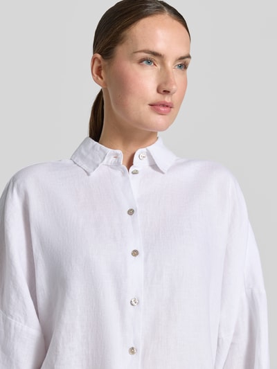 Frauenmodel trägt Leinenbluse mit überschnittenen Schultern von Christian Berg Woman in Weiß, Kentkragen, Knopfleiste, 3/4-Arm, Loose-Fit, Reines Leinen, Nahaufnahme Oberkörper.