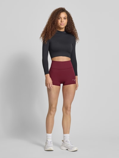 Frauenmodel trägt PUMA x HYROX - Leggings mit elastischem Bund von PUMA im Skinny-Fit, Elastischer-Material-Mix, Label-Print, bordeauxrot, Ganzkörperansicht von vorne.