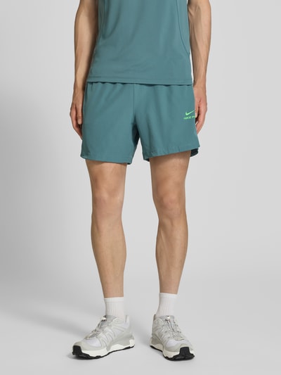 Männermodel trägt Shorts mit Logo und elastischem Bund von NIKE TRAINING in Türkis, elastischer Bund, Regular Fit, Ganzkörperansicht von vorne.