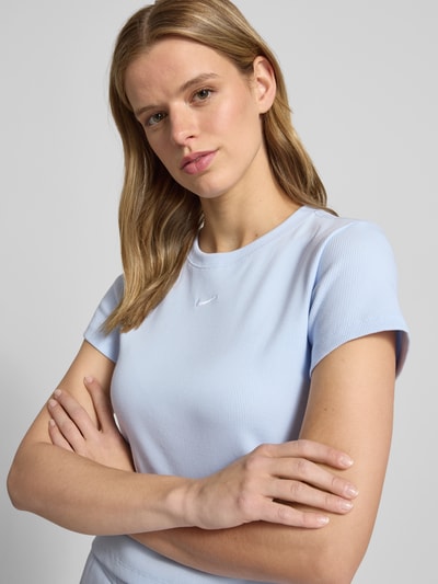 Frauenmodel trägt Cropped T-Shirt in Ripp-Optik mit Logo von Nike aus Baumwoll-Elasthan-Mix, Rundhalsausschnitt, Hellblau, Nahaufnahme Oberkörper. Rückenlänge bei Größe S: 49 cm.