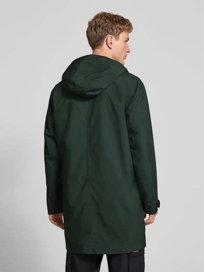 Männermodel trägt Regular Fit Mantel mit Kapuze Modell 'Brussel' von Helly Hansen in Dunkelgrün, glatte Textur, Ganzkörperansicht Rückansicht, Herren Mantel, Logo-Detail, Rückenlänge 96 cm, Schulterbreite 46 cm, Brustweite 51 cm, Ärmellänge 66 cm.