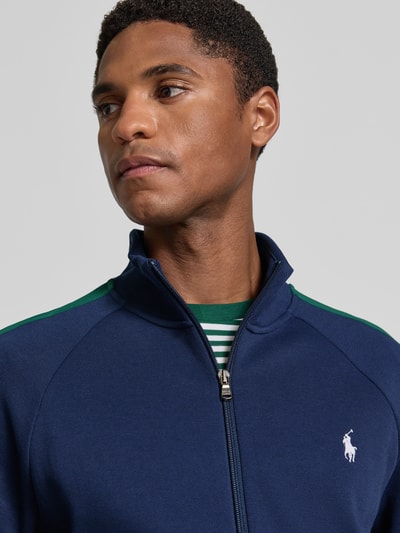 Männermodel trägt Regular Fit Sweatjacke aus Baumwoll-Mix von Polo Ralph Lauren in Dunkelblau mit grünen Akzenten, Nahaufnahme Oberkörper. Herren Sweatjacke.