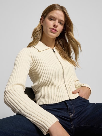 Kobiece modelka nosi Regular Fit kardigan rozpinany z prążkowanej dzianiny Model 'ELLY' od Only, efekt: jednolity kolor, wykładany kołnierz, dekolt w serek, długi rękaw, wykończenie: prążkowana dzianina. Ujęcie: z przodu, zbliżenie na górną część ciała.