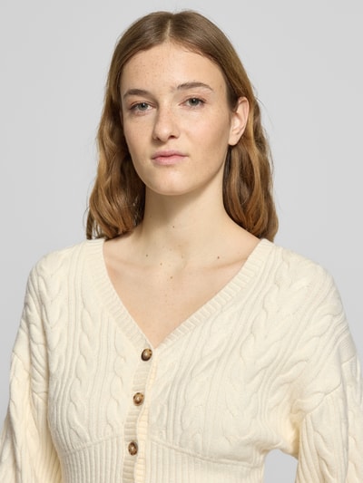 Kobiece modelka nosi Strickjacke mit Knopfleiste od Gina Tricot, kremowy kolor, krój regular fit, mieszanka wiskozy, żebrowane wykończenia, dekolt V, guziki, długość tyłu 48 cm, długość rękawa 52 cm, zbliżenie na górną część ciała