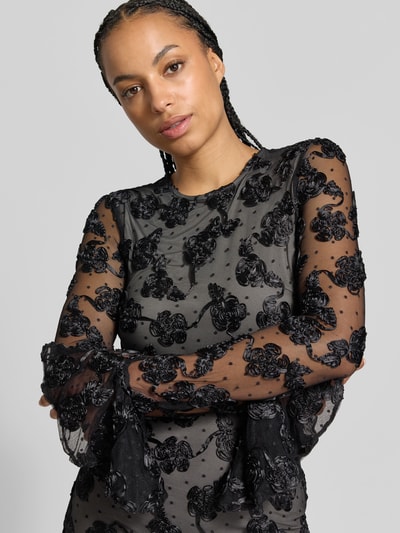 Frauenmodel trägt Minikleid mit floralem Besatz von ROTATE, schwarze Spitze, blickdichtes Unterkleid, Slim Fit, Nahaufnahme Oberkörper.