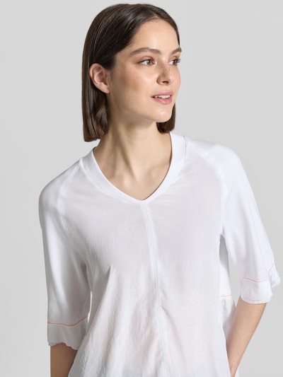 Frauenmodel trägt T-Shirt mit V-Ausschnitt und 3/4-Arm von Marc Cain, Baumwoll-Elasthan-Mix, Relaxed-Fit, Farbe Weiß, Nahaufnahme Oberkörper. Rückenlänge bei Größe 36: 60 cm.