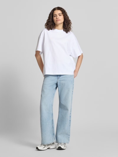 Frauenmodel trägt Oversized T-Shirt mit Motiv- und Logo-Print Modell 'NIVELLES' von Pegador aus weißer Baumwolle, Ganzkörperansicht von vorne.
