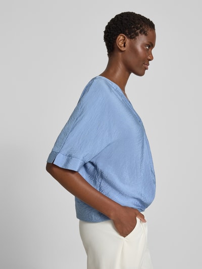 Frauenmodel trägt Blusenshirt mit V-Ausschnitt von Christian Berg Woman in Hellblau, leicht glänzende Struktur, Regular Fit, 1/2-Arm, Seitenansicht.