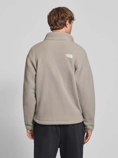 Männermodel trägt Regular Fit Fleecejacke mit Logo-Stitching von The North Face in Beige, Stehkragen, weiche Textur, Ganzkörperansicht Rückansicht. Herren Fleecejacke, Fleece, Eingrifftaschen, Reißverschluss, Rückenlänge 70 cm, Ärmellänge 63 cm.
