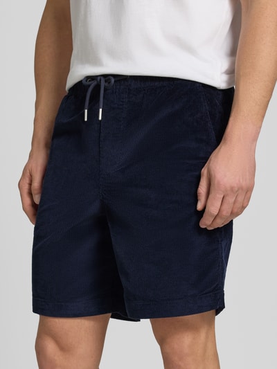 Mężczyzna nosi Regular Fit Sweatshorts aus Baumwoll-Mix von SELECTED HOMME, efekt: jednolity kolor, krój regular fit, tunel, ściągacz, kieszeń z tyłu, boczne wpuszczane kieszenie, wykończenie materiału: sztruks, mieszanka bawełny, zbliżenie na dolną część ciała z przodu.