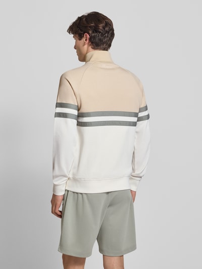 Männermodel trägt Trainingsjacke mit Label-Patch und Stehkragen Modell 'RIMINI' von ellesse, Baumwoll-Mix, Regular-Fit, Rückenlänge 71 cm, Ärmellänge 65 cm, creme und beige mit grauen Streifen, Eingrifftaschen, Ganzkörperansicht Rückansicht.