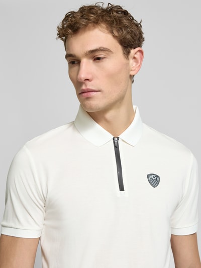 Männermodel trägt Slim Fit Poloshirt aus Viskose-Mix von EA7 Emporio Armani, weiß, Logo-Detail, Polokragen, Nahaufnahme Oberkörper.