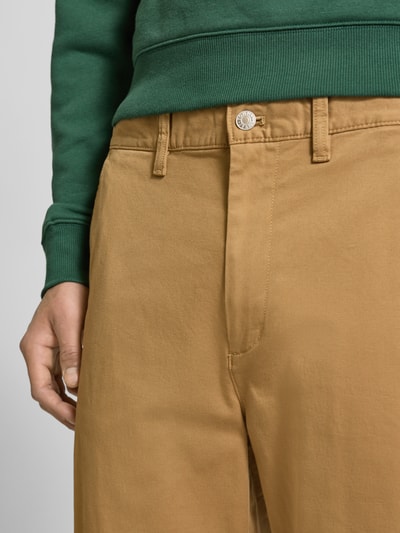 Männermodel trägt Tapered Chino aus Baumwoll-Mix Modell 'SONNY' von Tommy Jeans, efekt: jednolity kolor, krój regular fit, wpuszczane kieszenie, zapięcie na guzik i zamek błyskawiczny, mieszanka bawełny, splot twill, zbliżenie na pas i kieszenie, detal, perspektywa: nahaufnahme obszaru pasa