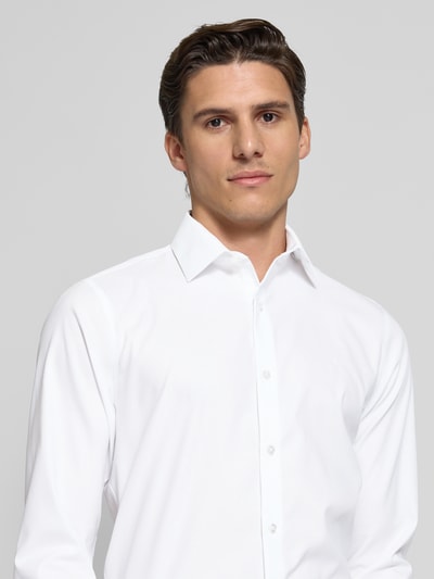 Männermodel draagt Slim Fit Business-Hemd mit kentkraag van CK Calvin Klein, wit, mix van katoen en elastaan, structuurpatroon, gestikt logo, doorlopende knoopsluiting, nahaufnahme oberkörper.