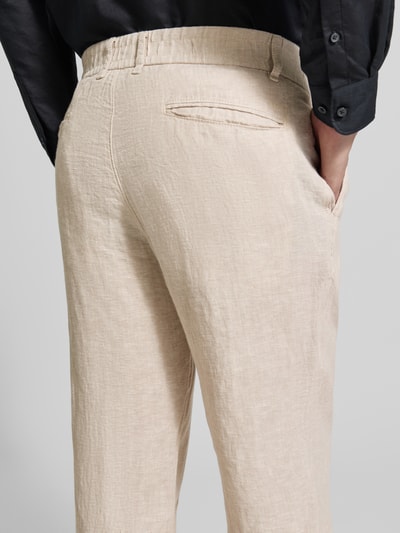 Mannenmodel draagt Tapered Fit Leinenhose met steekzakken van MCNEAL, zuiver linnen, paspelzakken achter, bandwijdte maat M 45 cm, binnenbeenlengte maat M 76 cm, detailopname achterkant.