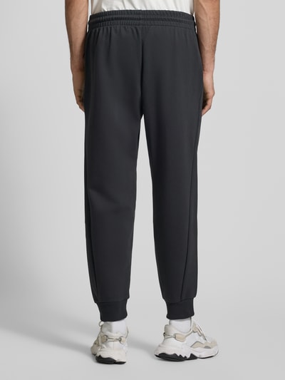 Männermodel trägt Sweatpants mit Logo und elastischem Bund von adidas Sportswear, Materiaalmix met katoen, regular fit, elastische band, tunnelkoord, binnenbeenlengte bij maat M 75 cm, Ganzkörperansicht Rückansicht.
