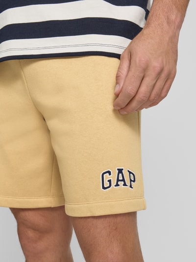 Männermodel trägt Sweatshorts mit Logo und elastischem Bund von GAP in Beige, Baumwoll-Mix, Regular-Fit, Nahaufnahme Oberschenkel.