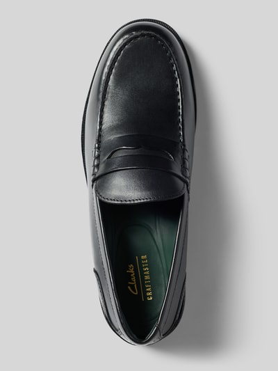 Produktfoto, Slipper aus beschichtetem Leder Modell 'CraftJames' von Clarks in Schwarz, abgerundete Form, glatte Sohle, Zierriemen, Vogelperspektive