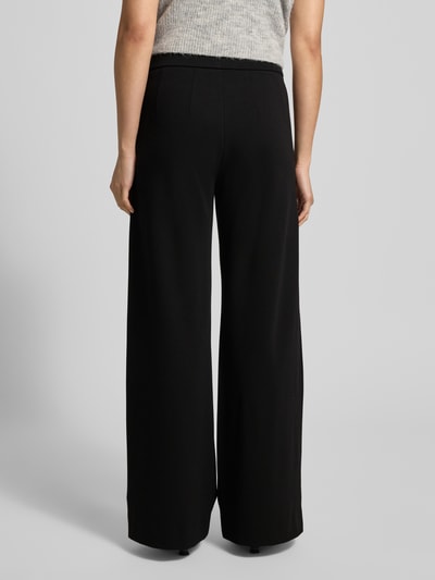 Frauenmodel trägt schwarze Stoffhose mit französischen Eingrifftaschen Modell 'NALEY' von SEDUCTIVE, lockerer Schnitt, Ganzkörperansicht Rückansicht.