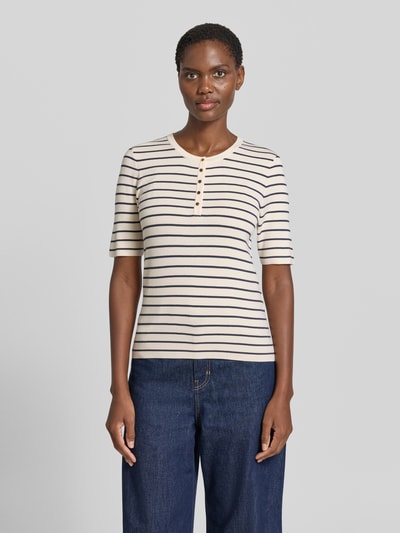 Vrouwenmodel draagt gebreid shirt uit viscosemix model 'Aliz Caliz' van MOS MOSH, nauwsluitend, ronde hals, 1/2-mouwen, knoopsluiting, ruglengte maat S 58 cm, mouwlengte maat S 27 cm, crèmekleur met zwarte strepen, fijngebreide structuur, voorkant geheel zichtbaar, Ganzkörperansicht van voren.