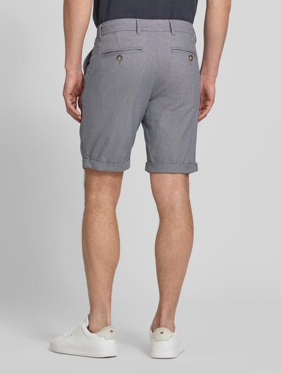 Männermodel trägt Slim Fit Chinoshorts aus Baumwoll-Mix Modell 'LUTON' von SELECTED HOMME in Grau, feine Webstruktur, Ganzkörperansicht Rückansicht