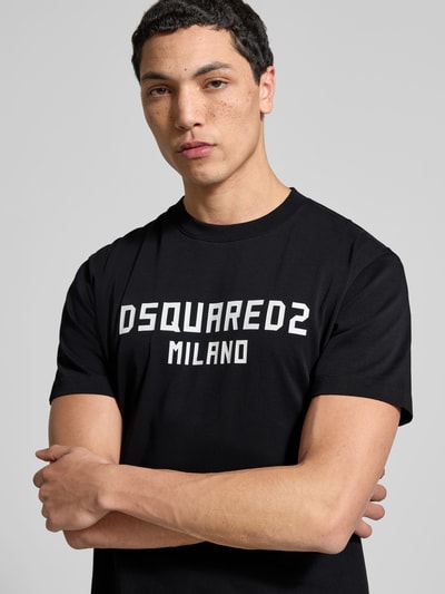 Männermodel trägt Cool Fit T-Shirt aus reiner Baumwolle von Dsquared2, schwarz mit Statement-Print, semitransparente Optik, Nahaufnahme Oberkörper.