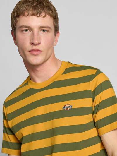 Männermodel trägt T-Shirt mit Label-Stitching Modell 'RIVERGROVE' van Dickies in geel met olijfgroene strepen, regular fit, ronde hals, katoen, Nahaufnahme Oberkörper
