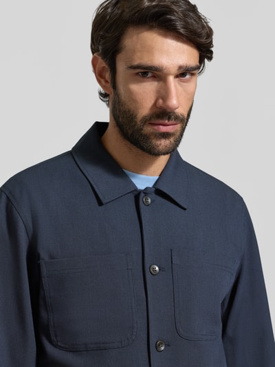 Männermodel trägt Regular Fit Hemdjacke mit Brusttaschen Modell 'Marseille' von Les Deux in Dunkelblau, Nahaufnahme Oberkörper. Materialmix mit Viskose-Anteil, Kentkragen, Knopfleiste, gerader Schnitt.