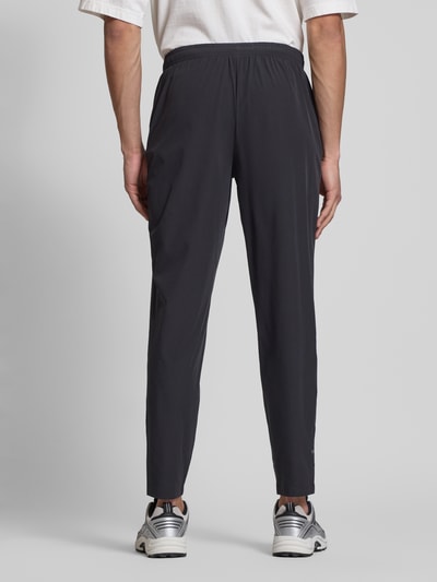 Männermodel trägt Trackpants mit elastischem Bund Modell 'EVARO' von Ellesse in Schwarz, Regular Fit, Material-Mix, Ganzkörperansicht Rückansicht.