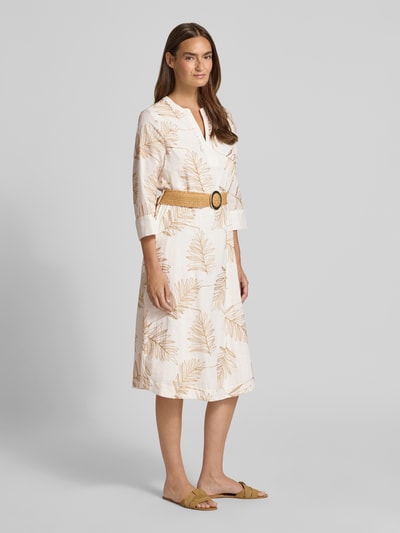 Modelka kobieca nosi Tailliertes Freizeitkleid aus Baumwoll-MIx od s.Oliver BLACK LABEL w naturalnych beżowo-białych barwach, liściasty wzór, tekstura miękka, widok całej sylwetki z przodu.