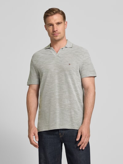Männermodel trägt Regular Fit Poloshirt aus reiner Baumwolle von Tommy Hilfiger in Melange-Optik mit Logo-Stitching, Ganzkörperansicht von vorne.