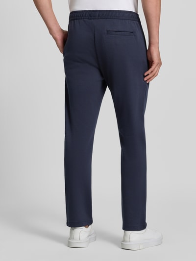 Männermodel trägt Straight Fit Hose mit Baumwoll-Anteil Modell 'Parker' von MCNEAL in Dunkelblau, Gesäßtasche, elastischer Bund, Ganzkörperansicht Rückansicht.