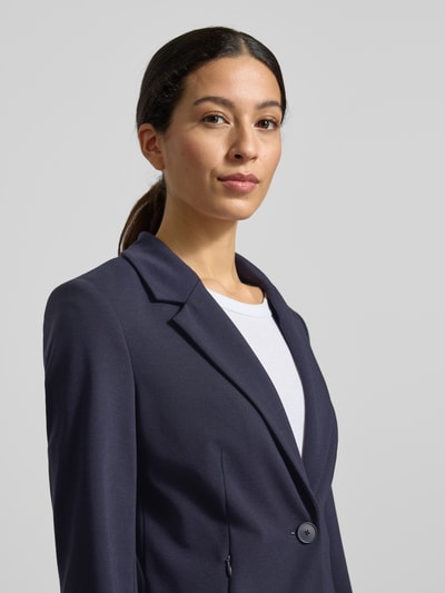 Frauenmodel trägt Blazer mit Reverskragen von comma in Dunkelblau, glatte Textur, Knopfverschluss, Nahaufnahme Oberkörper. Viskose-Mix mit Stretch-Anteil, Slim Fit, Nahtreißverschlusstaschen.