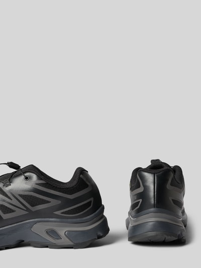Produktfoto, Sneaker mit profilierter Sohle Modell 'XT-EVR' von Salomon in Schwarz, sichtbare Schnürung, Logo, strukturierte Oberfläche, abgerundete Spitze, Sohlenprofil gut erkennbar, neutrale graue Hintergrundfläche, Absatzhöhe 4 cm, Schafthöhe 6 cm, Schaftweite 7 cm