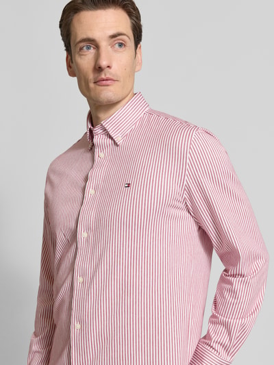 Männermodel trägt Regular Fit Freizeithemd aus Baumwoll-Mix von Tommy Hilfiger in Rot-Weiß, Button-Down-Kragen, Nahaufnahme Oberkörper.