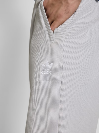 Männermodel trägt Straight Fit Sweatpants mit structuurpatroon model 'Essentials' van adidas Originals, materiaalmix met katoen, steekzakken, detailopname.