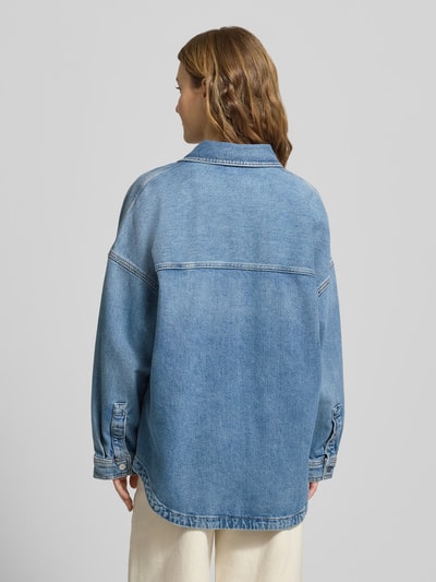Vrouwenmodel draagt Jeansbluse mit Hemdblusenkragen van Calvin Klein Jeans in lichte denimkleur, losse fit, puur katoen, rugaanzicht, context: casual damesblouse met blinde knoopsluiting, achterkantlengte maat S 73 cm, mouwlengte 47 cm.