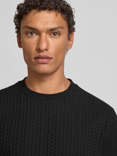 Männermodel trägt T-Shirt mit geripptem Rundhalsausschnitt von Emporio Armani, Reine Baumwolle, Regular-Fit, Label-Stitching, Nahaufnahme Oberkörper.