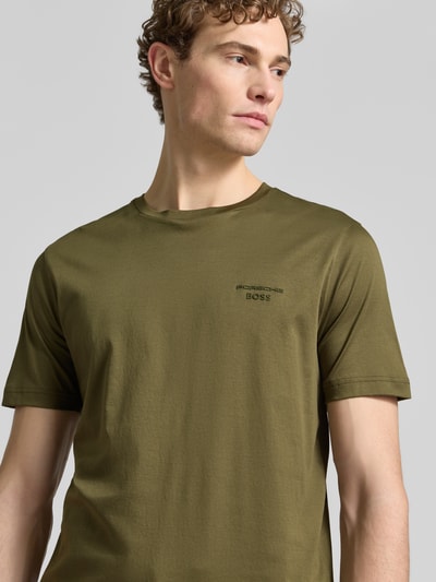 Męski model nosi Regular Fit T-Shirt aus reiner Baumwolle Modell 'PS Spirit 70 Grx' von BOSS Green X PORSCHE, kolor jednolity, krótki rękaw, okrągły dekolt, materiał 4way stretch, label-aplikacja, bawełna, nahaufnahme górnej części ciała.