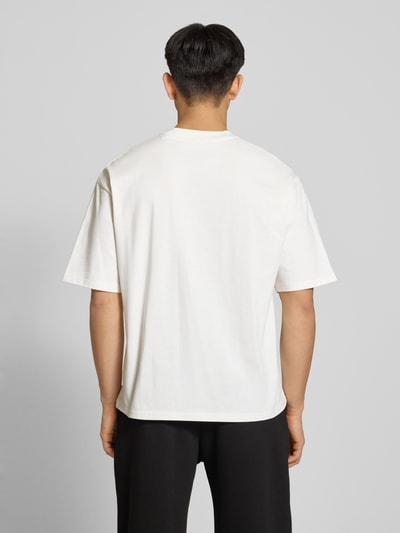 Męski model nosi T-Shirt mit Label-Stitching und Rundhalsausschnitt od REVIEW z bawełny, krój relaxed fit, długość tyłu 70 cm, całkowity widok z tyłu.
