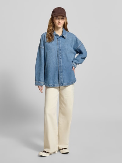 Vrouwenmodel draagt 'Jeansbluse mit Hemdblusenkragen' van Calvin Klein Jeans in losse fit, lichtblauwe denim, pure katoen, hemdkraag, vooraanzicht hele lichaam.