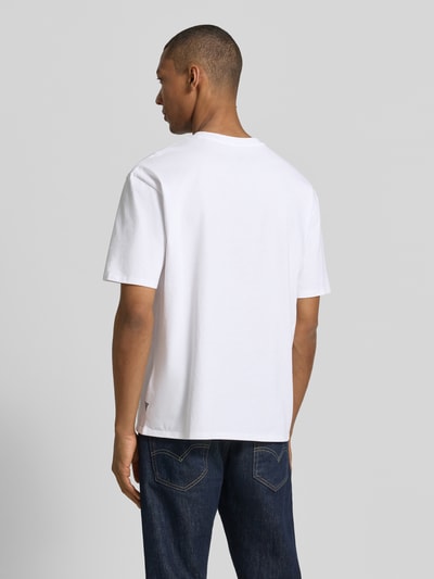 Männermodel trägt T-Shirt mit Motiv-Print und Rundhalsausschnitt von Guess aus reiner Baumwolle im Regular-Fit, Rückenlänge 68 cm, Ganzkörperansicht Rückansicht.