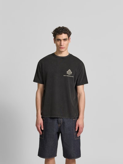 Männermodel trägt Relaxed Fit T-Shirt aus Baumwoll-Mix von Don´t Waste Culture in Schwarz mit Rundhalsausschnitt, Used-Look, Label-Details, Rückenlänge 68 cm bei Größe M, Ganzkörperansicht von vorne.