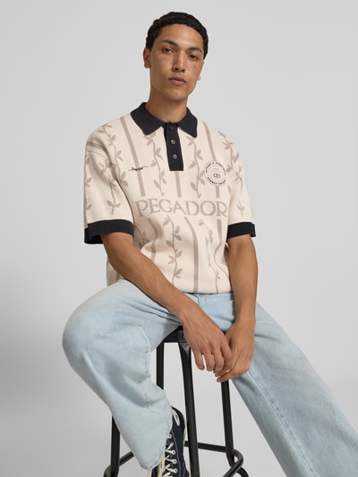 Männermodel trägt Relaxed Fit Poloshirt mit Logo-Stitchings Modell 'Kinsale' von Pegador aus Reine Baumwolle, Ganzkörperansicht von vorne.
