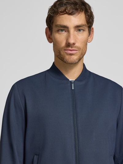 Männermodel trägt Blouson mit Zweiwege-Reißverschluss von bugatti in Dunkelblau, fein strukturierter Material-Mix, Nahaufnahme Oberkörper, Regular Fit. Material mit Stretch-Anteil, Stehkragen, Eingrifftaschen, Maße bei Größe 50: Rückenlänge 66 cm, Schulterbreite 41 cm, Brustweite 47 cm, Ärmellänge 65 cm.