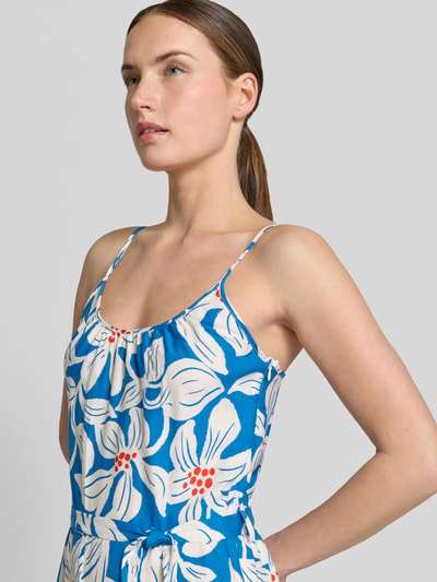 Vrouwenmodel draagt Jumpsuit uit zuiver viscose met spaghettibandjes model 'Rylie' van GUIDO MARIA KRETSCHMER WOMAN, getailleerd model, ronde hals, strikceintuur, maat 36, blauwe en witte bloemenprint, bustwijdte 32 cm, ruglengte 128 cm, totale lengte 128 cm, binnenbeenlengte 78 cm. Nahaufnahme bovenlichaam.