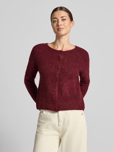 Frauenmodel trägt Strickjacke aus Alpaka-Mix von MOS MOSH in Bordeaux mit geripptem Rundhalsausschnitt und Knopfleiste, lockere Passform, Nahaufnahme Oberkörper.