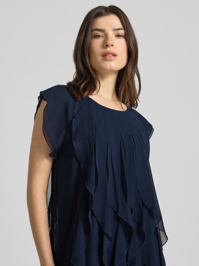 Modelka nosi Relaxed Fit Minikleid mit Allover-Rüschenbesatz od Vera Mont w granatowym kolorze, okrągły dekolt, krótkie rękawy, halka pod spódnicę, szerokość w rozmiarze 36: 39 cm, długość tyłu: 90 cm, półzbliżenie przód.