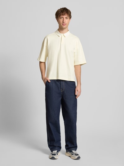 Männermodel trägt Regular Fit T-Shirt mit Polo-Kragen von adidas Originals in Creme, reine Baumwolle, dezentes Logo-Stitching, Ganzkörperansicht von vorne.